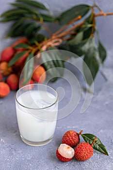 Sweet lychee juice on the gray background Closeup of fresh lychee juice with fruits