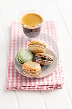 Sweet macaron dessert and coffee cup. Colorful macarons on plate on checkered napkin