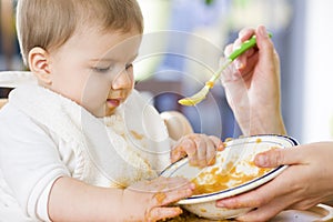 Sweet messy baby boy playing with food while eating.