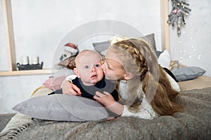 Sweet moment between a big sister and her baby brother. The sister is kissing his cheek. Love sisters. parental care and