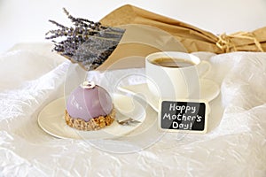 Sweet morning breakfast time concept, beautiful violet cake, cup of coffee near plate with the note Happy Mother`s Day