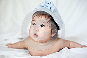 Sweet Newborn Baby in Blue Bobble Hat Lies on Bed