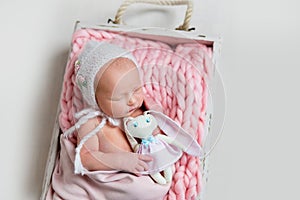 Sweet newborn baby girl sleeping and embracing her toy