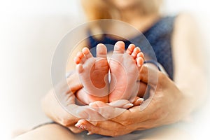 Sweet newborn baby`s feet in woman`s arms