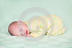 Sweet newborn baby sleeping on green blanket