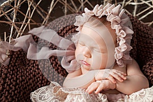 Sweet newborn baby sleeping.  Newborn girl 3 weeks old lying in a basket with knitted plaid. Portrait of pretty  newborn girl.