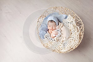 Sweet newborn baby sleeps in a basket. Beautiful newborn boy with bear toy. Copy space