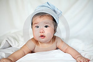 Sweet Newborn Baby in White Hat Lies on Bed