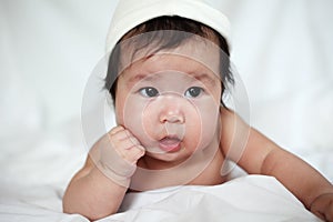 Sweet Newborn Baby in White Hat Lies on Bed