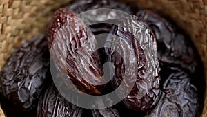 Sweet organic Medjool dates with wrinkled peel in rustic bowl. Macro.