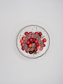 Sweet organic red cherries with water droplets in a glass bowl isolated on white background