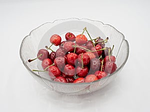 Sweet organic red cherries with water droplets in a glass bowl isolated on white background