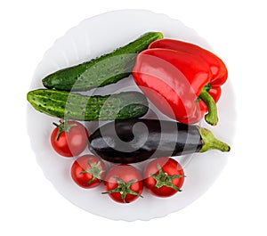 Sweet pepper, eggplant, cucumbers and tomatoes in plate isolated on white. Top view