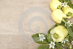 sweet pepper with leaves and flowers on a wooden table