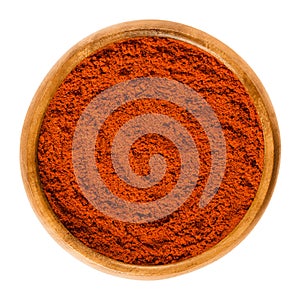 Sweet pepper red paprika powder in wooden bowl over white