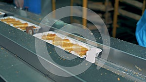 Sweet pies in foil trays move into a packing machine.