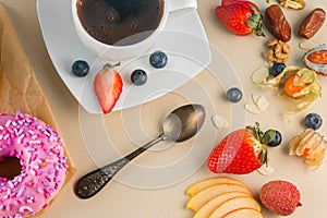 Sweet pink donut with cup of aroma coffee, fruits and berries on light stone background.