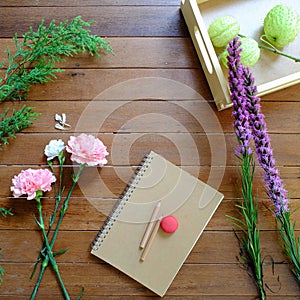 Sweet Pink and Purple flowers with notebook and pencils on wood table background