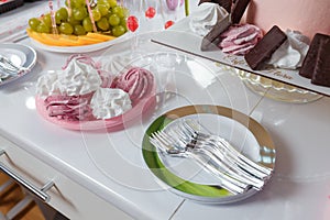 Sweet pink white zephyr or marshmallow and fruit cut platter, orange and grapes. Unfocused glassess on background. Wedding