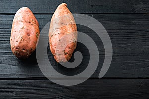 Sweet potato or batat, on black wooden background with space for text