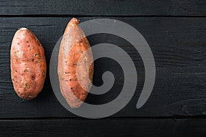 Sweet potato or batat, on black wooden background, top view with space for text