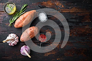 Sweet potato or batat with herbs on old wooden table, top view with space for text