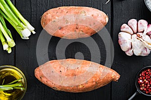 Sweet potato or batat with ingredients, on black wooden background, top view