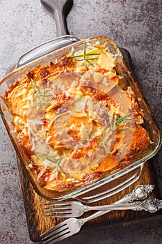Sweet potato casserole with cheddar cheese and rosemary close-up in a glass form. Vertical top view