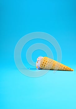 a sweet potato flavor ice cream cone in a melting process on blue background vertical composition