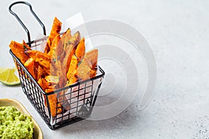 Sweet potato fries in metal basket with guacamole gray background. Vegan food concept