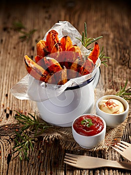 Sweet potato fries seasoned herbs and sea salt in enamel mug on a wooden table