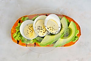 Sweet potato toast with avocado, eggs and chia seeds over marble