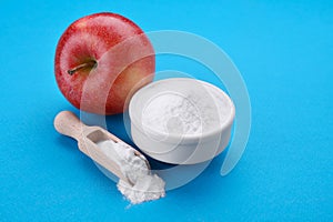 Sweet powdered fructose and fresh apple on light blue background