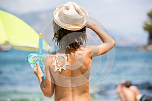 Sweet preschool boy, holding scuba mask with sunscream applied on his back, ready for the harsh sun photo