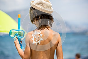 Sweet preschool boy, holding scuba mask with sunscream applied on his back, ready for the harsh sun photo