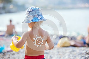 Sweet preschool boy, holding scuba mask with sunscream applied on his back, ready for the harsh sun photo