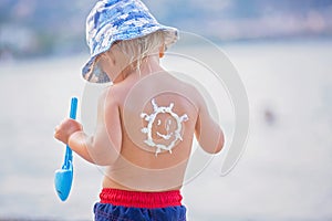 Sweet preschool boy, holding scuba mask with sunscream applied on his back, ready for the harsh sun photo