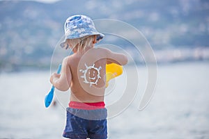 Sweet preschool boy, holding scuba mask with sunscream applied on his back, ready for the harsh sun photo