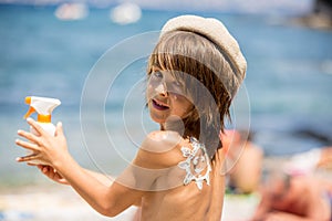 Sweet preschool boy, holding scuba mask with sunscream applied on his back, ready for the harsh sun photo