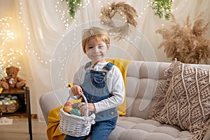 Sweet preschool boy in studio, playing with, egg for Easter and eating chocolate, child on Easter holiday