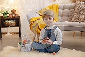 Sweet preschool boy in studio, playing with, egg for Easter and eating chocolate, child on Easter holiday