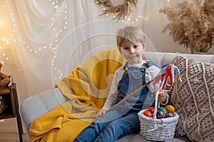 Sweet preschool boy in studio, playing with, egg for Easter and eating chocolate, child on Easter holiday