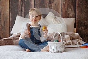 Sweet preschool boy in studio, playing with, egg for Easter and eating chocolate, child on Easter holiday