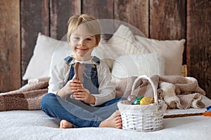 Sweet preschool boy in studio, playing with, egg for Easter and eating chocolate, child on Easter holiday