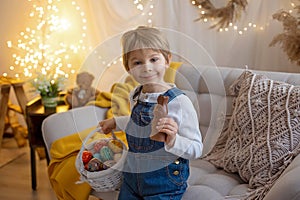 Sweet preschool boy in studio, playing with, egg for Easter and eating chocolate, child on Easter holiday