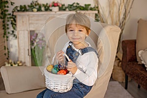 Sweet preschool boy in studio, playing with, egg for Easter and eating chocolate, child on Easter holiday