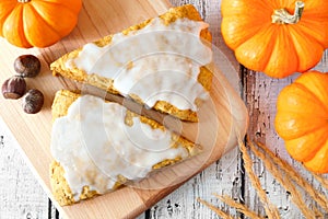 Sweet pumpkin scones with frosting, overhead view on wood