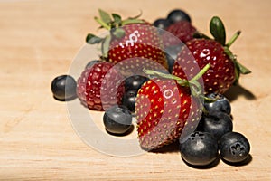 Sweet Raspberries, blueberries, strawberries on a wood plank