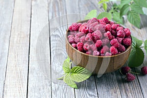 Sweet raspberries in bowl on wooden table. Close up, high resolution product photo