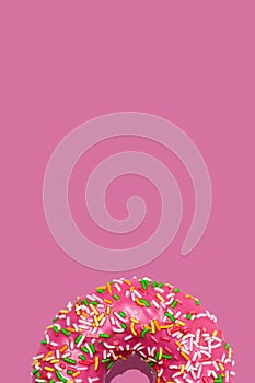 Sweet raspberry doughnuts or donuts with icing and with colorful sugar sprinkles on pastel pink background